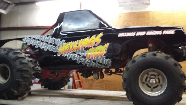 A Monster Truck is Parked in a Garage With a Ladder in the Background