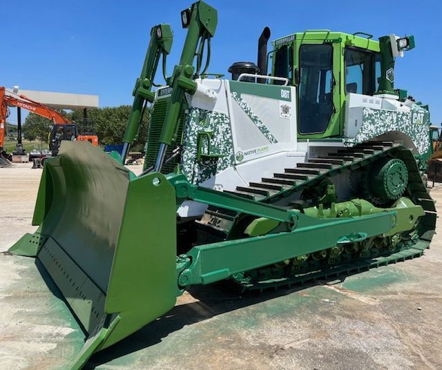 A green and white bulldozer is parked in a parking lot