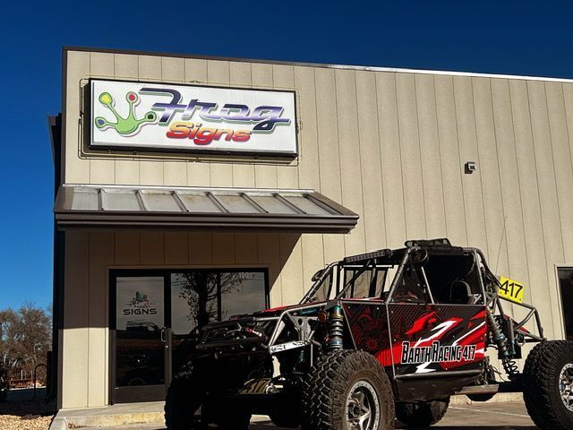 A red and black atv is parked in front of a building