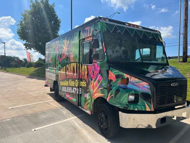 A colorful food truck is parked in a parking lot
