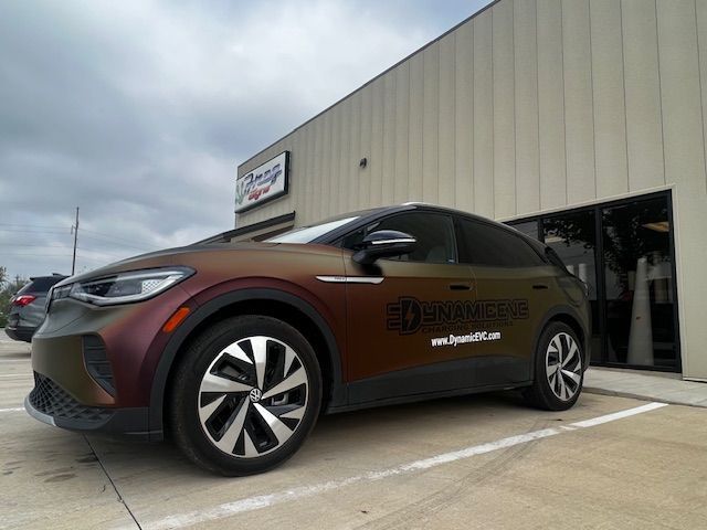 A volkswagen id 4 is parked in a parking lot in front of a building