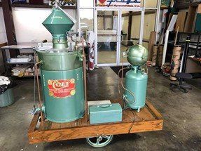 A Green Machine is Sitting on a Wooden Cart in a Room