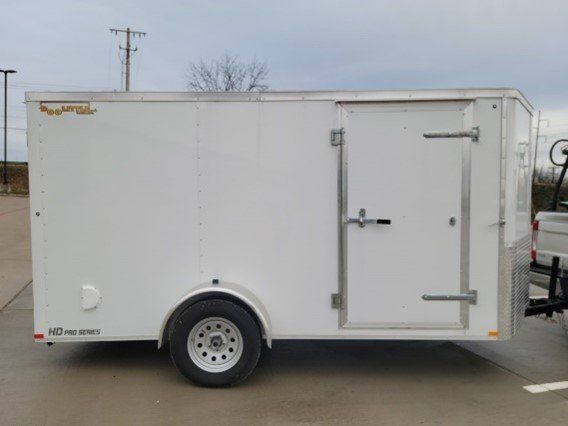 A White Trailer is Parked in a Parking Lot Next to a Truck