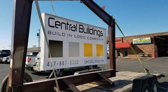 A sign for central buildings is being lifted by a crane
