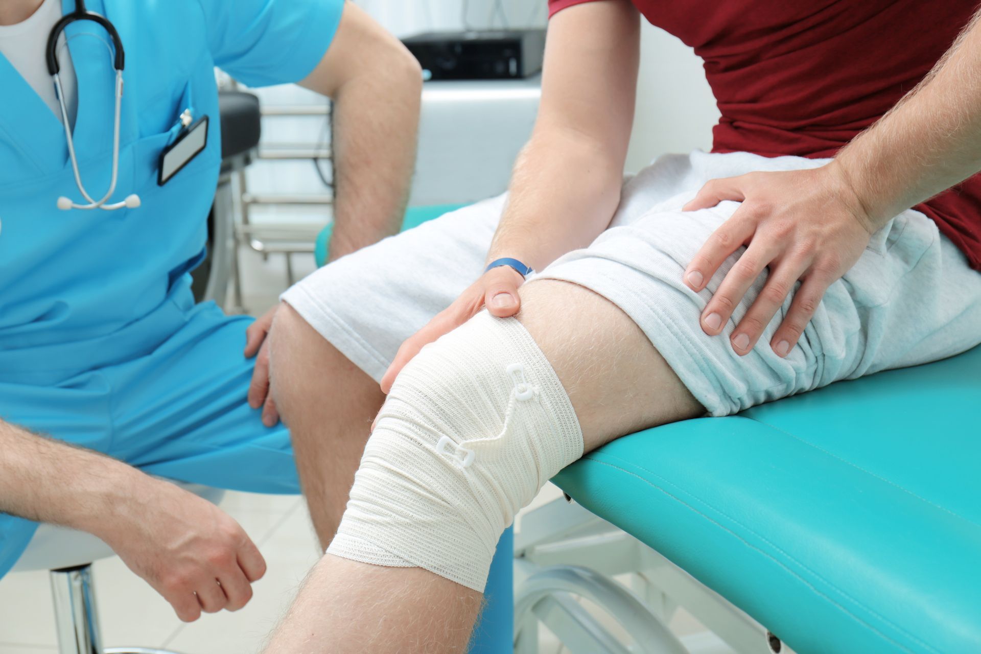 Knee bandage being checked by a medical professional in a clinic exam room