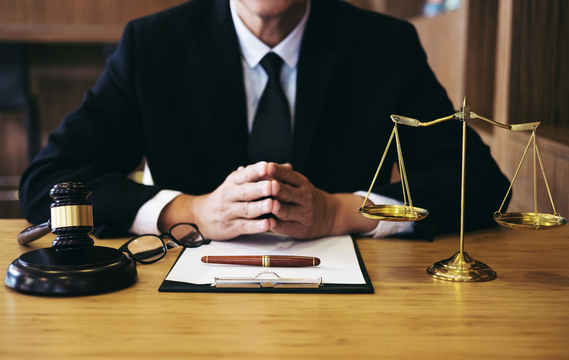 Attorney seated at a desk with legal scales, gavel, and documents in a law office