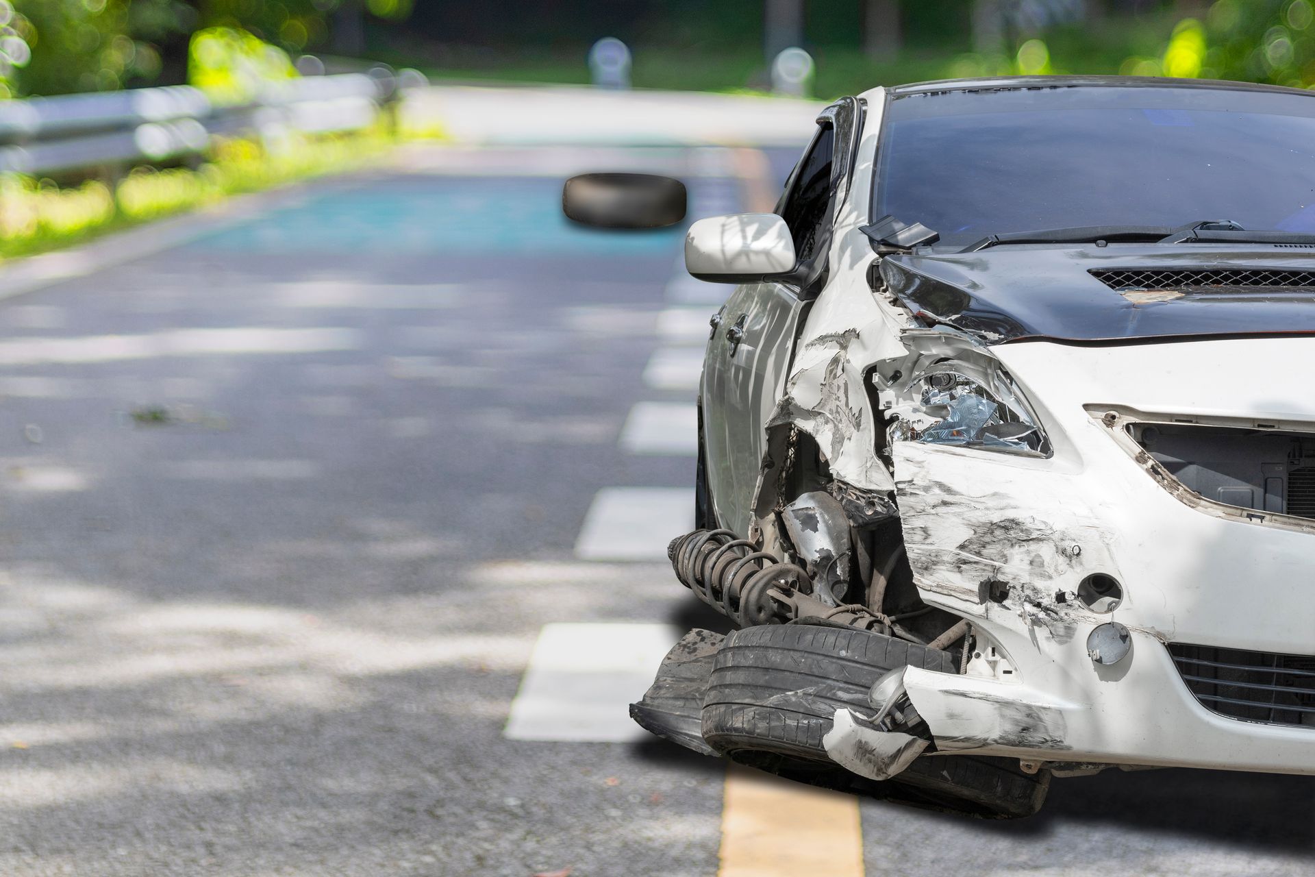 Damaged white car with crumpled front end on a road after a collision