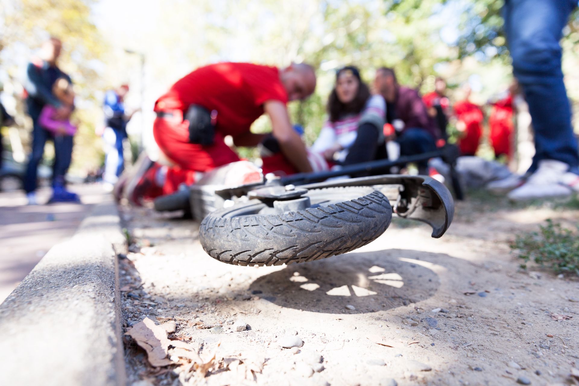 Cracked tire on a bicycle lying on a sidewalk with people blurred in the background