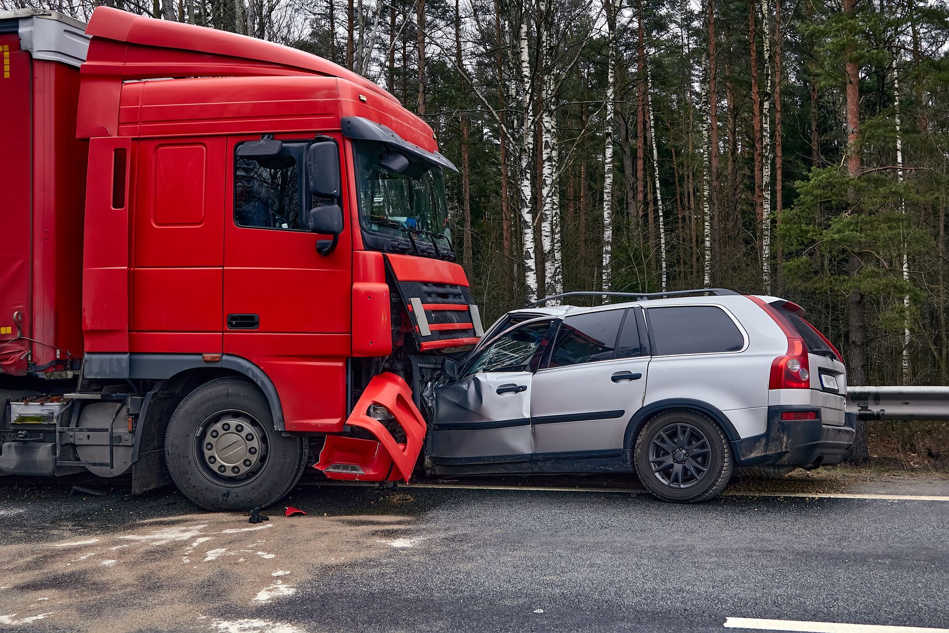 Red truck collided with a white SUV on a roadside near a forest.
