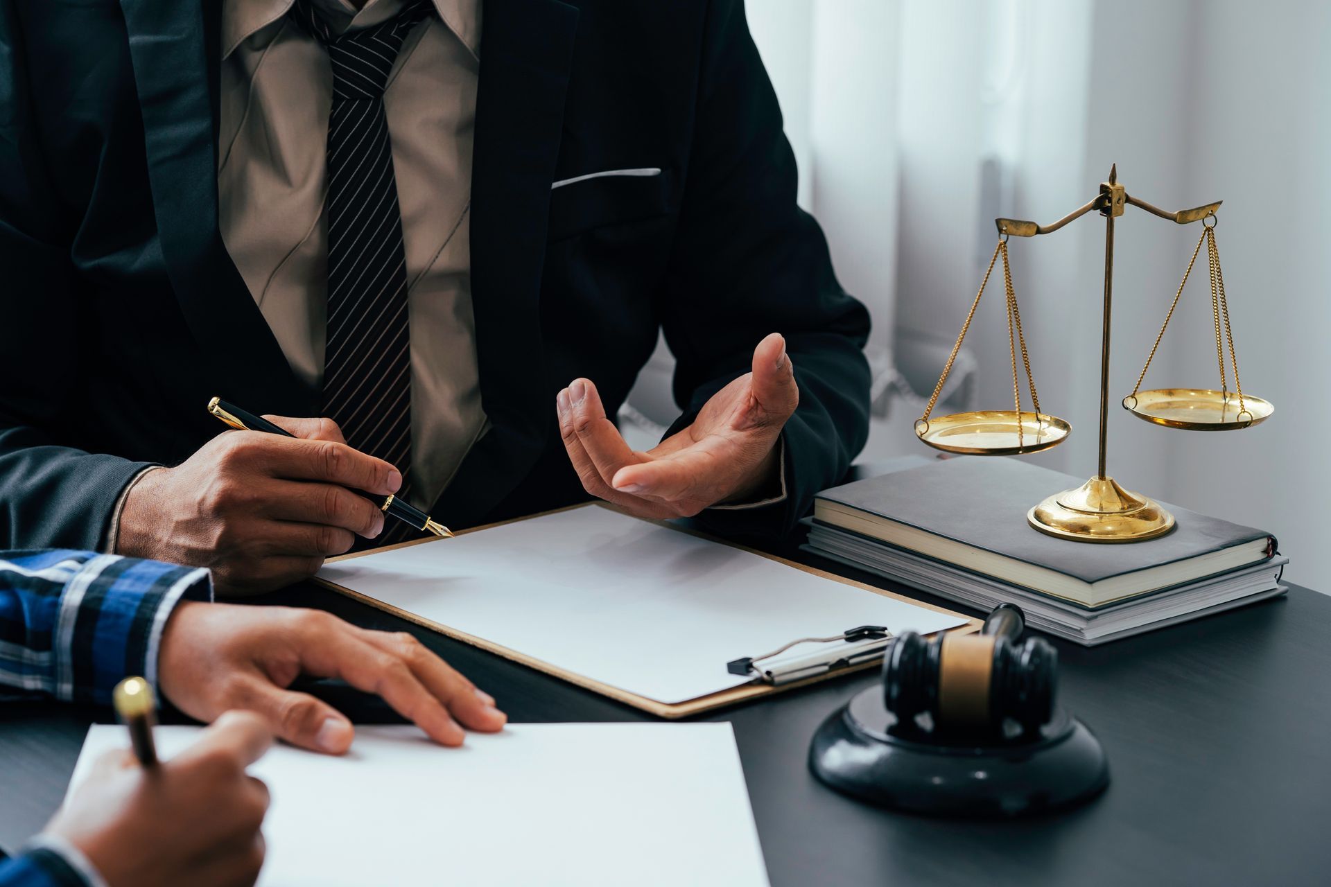 Lawyer in a dark suit discussing a case at a desk with scales of justice and a gavel