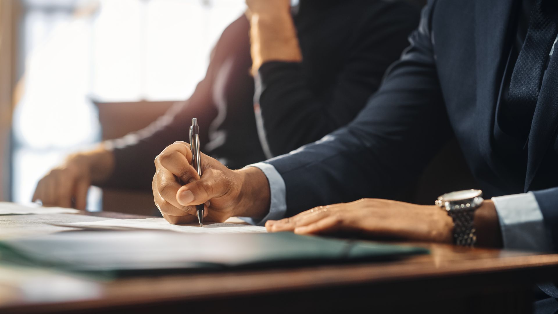 Businesspeople signing a document at a desk in an office