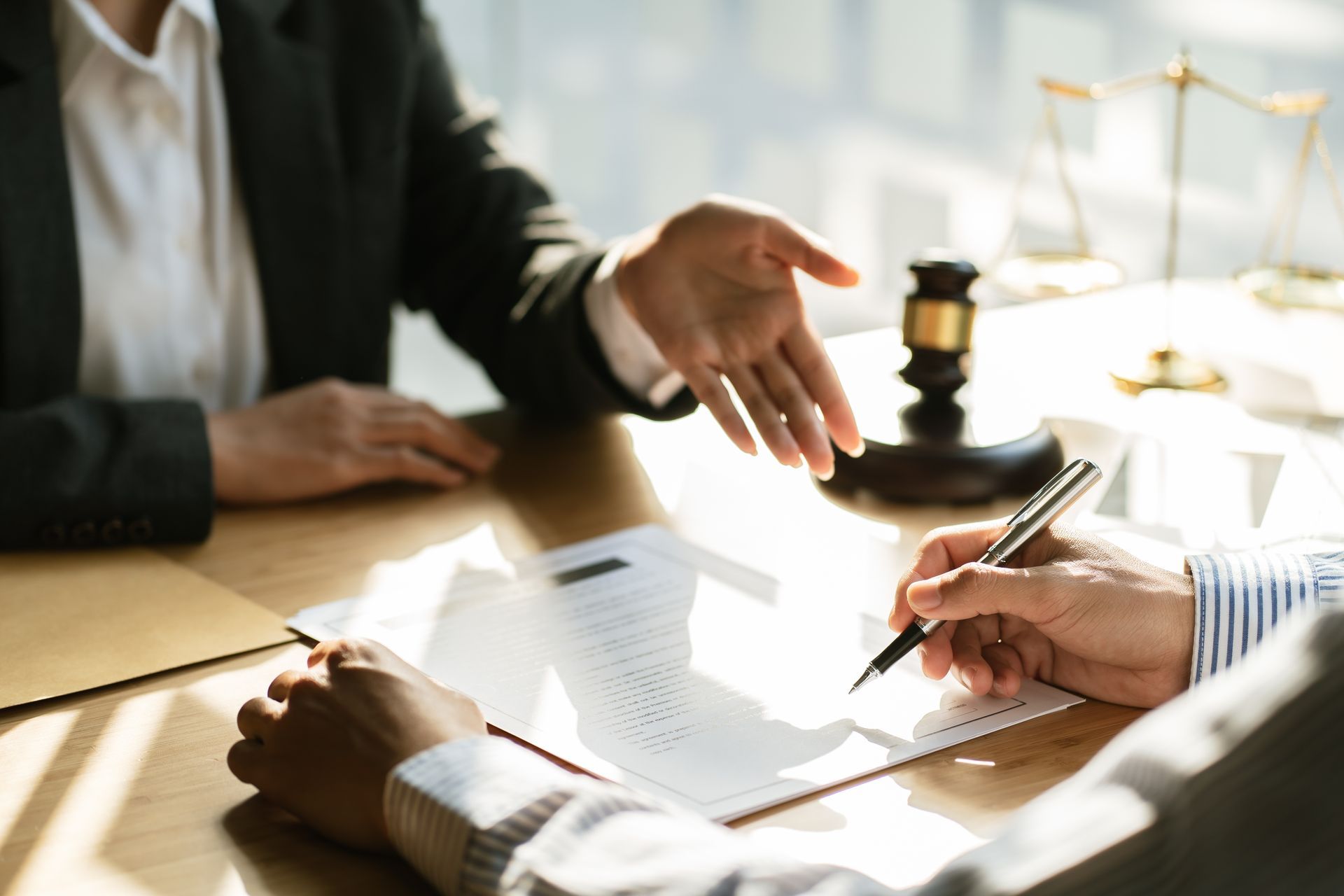 People signing a legal document at a desk with a gavel in the background