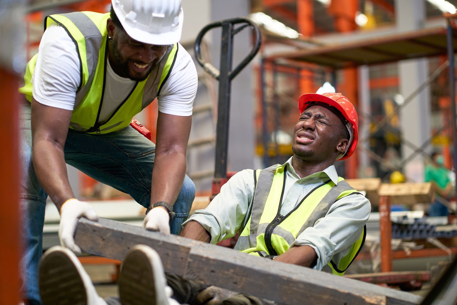 Two construction workers in hard hats and safety vests moving a long beam at a worksite
