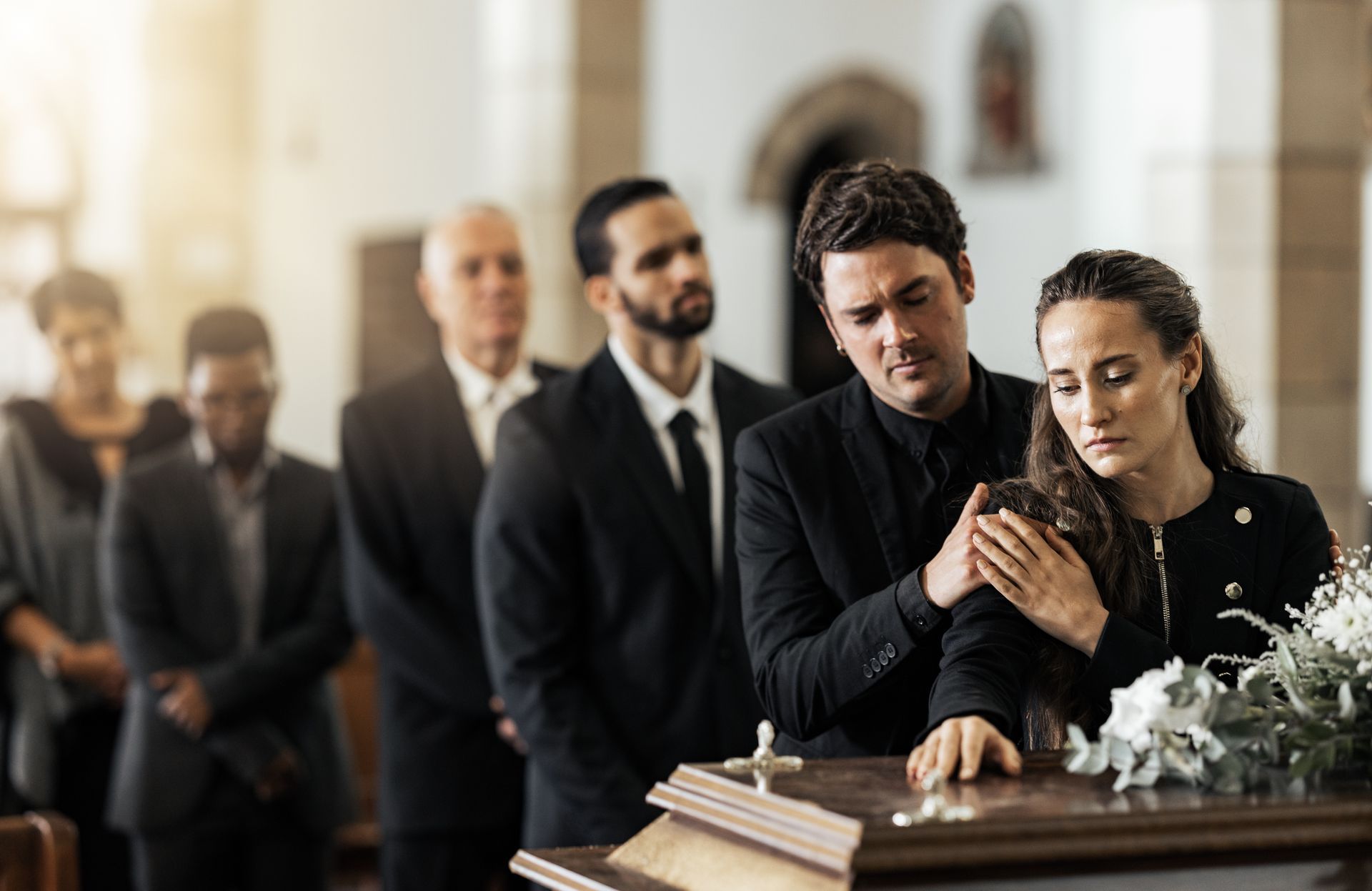 Mourners standing by an open casket during a funeral service
