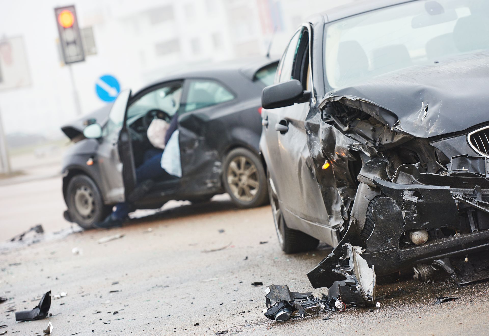 Two damaged cars after a collision, with front-end wreckage and debris on the road.