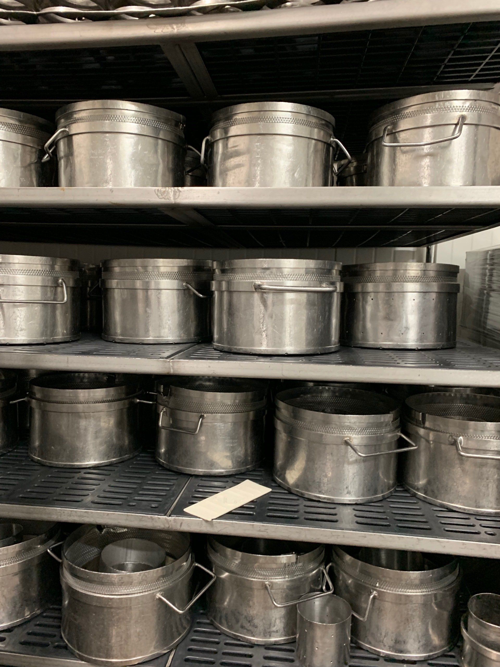 A shelf filled with lots of stainless steel pots and pans.