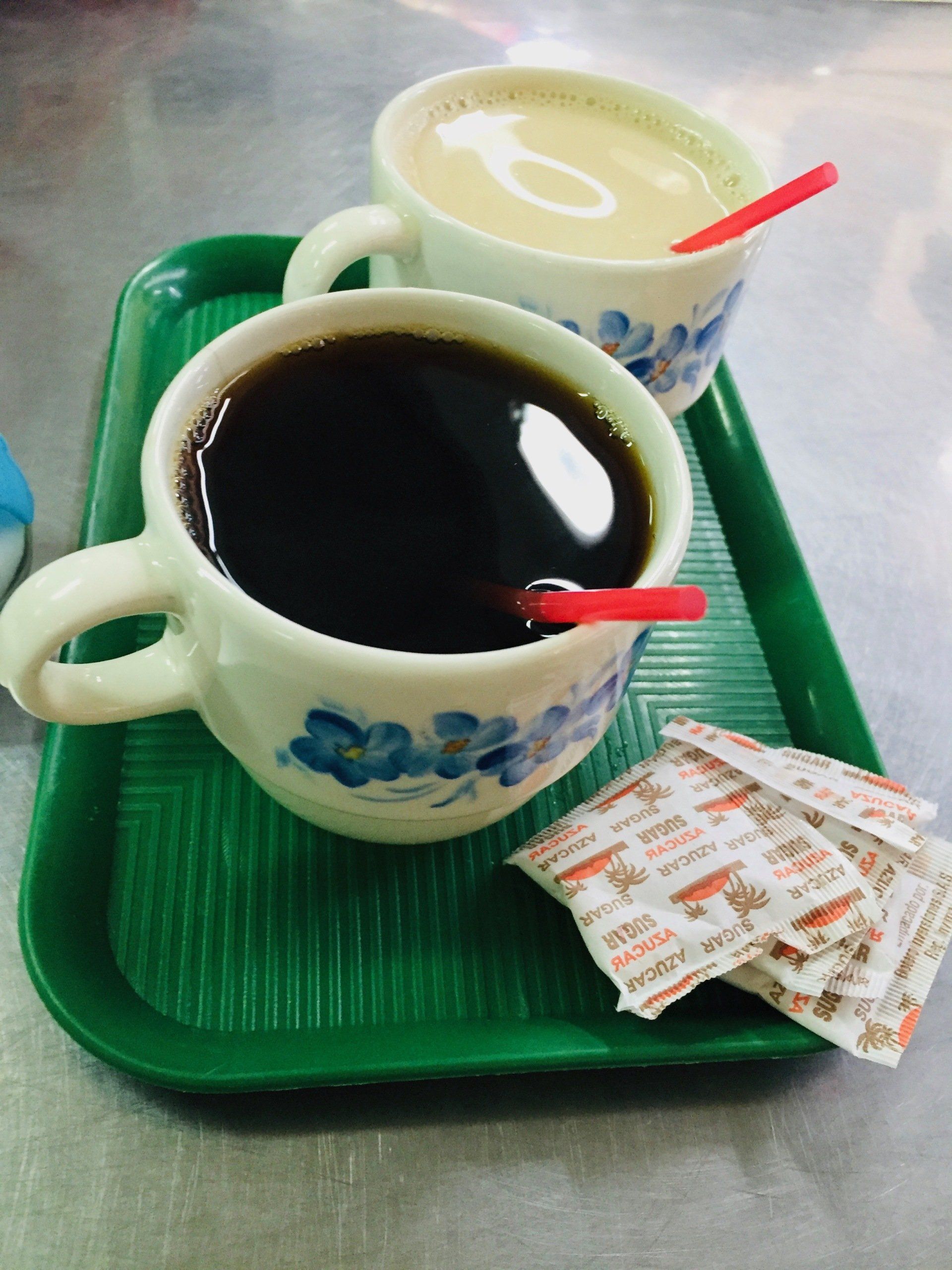 Two cups of coffee are on a green tray