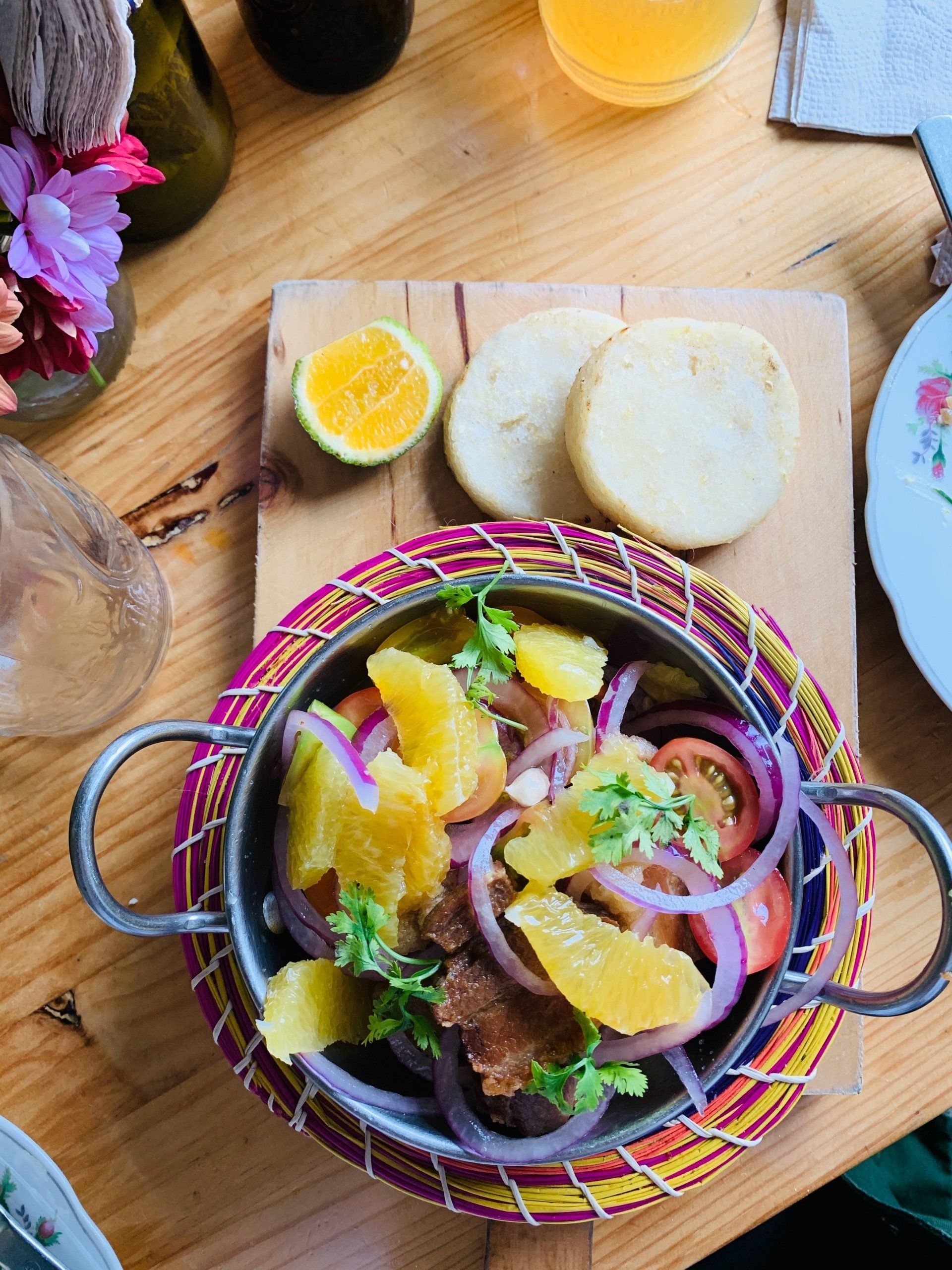 A bowl of food with oranges and onions on a wooden table.