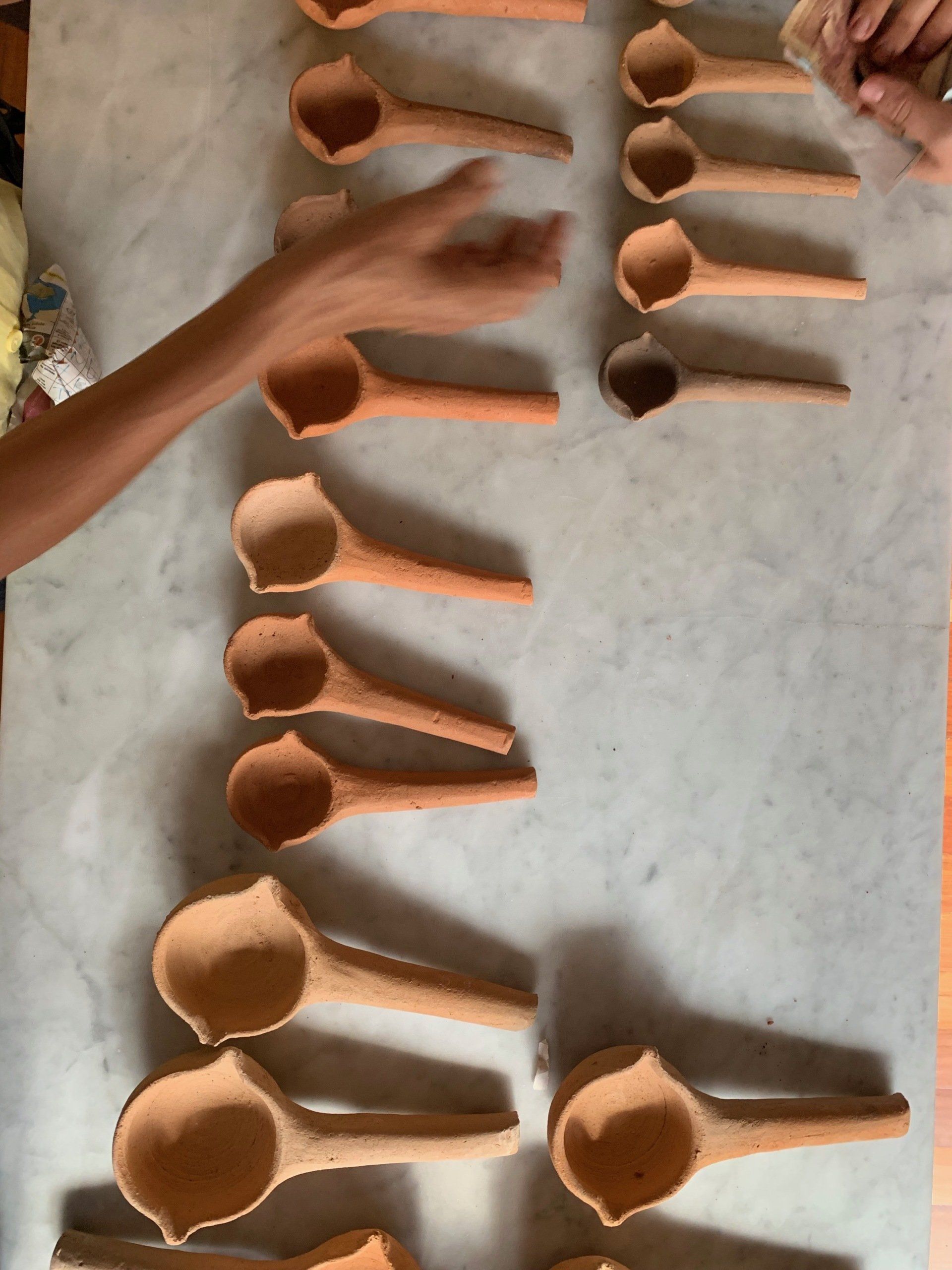 A row of clay spoons are lined up on a table