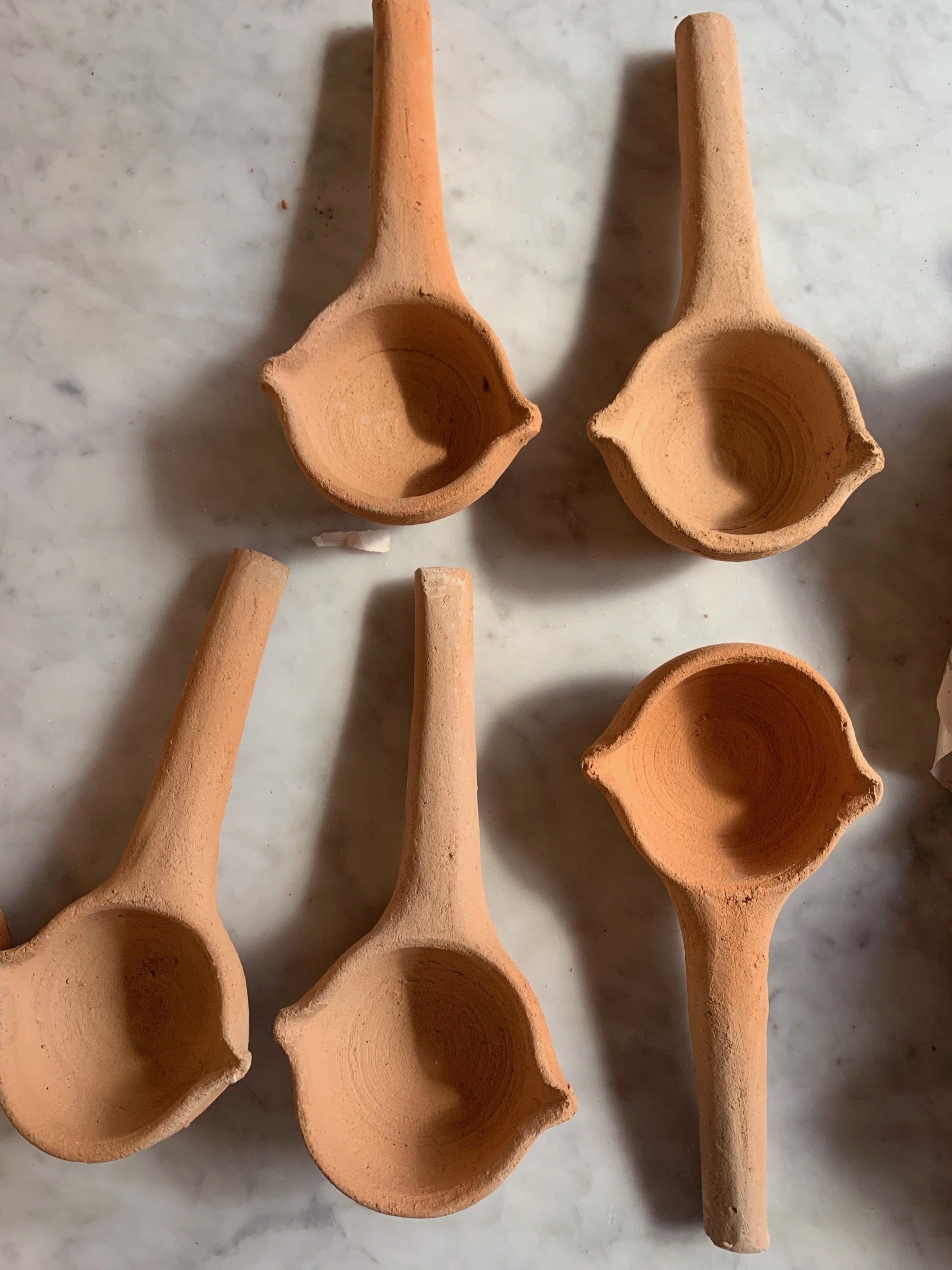 A group of clay spoons are lined up on a table