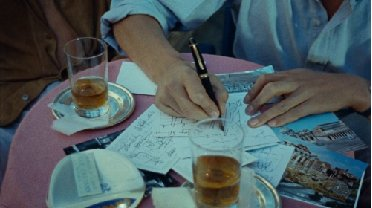 A person is sitting at a table writing on a piece of paper.