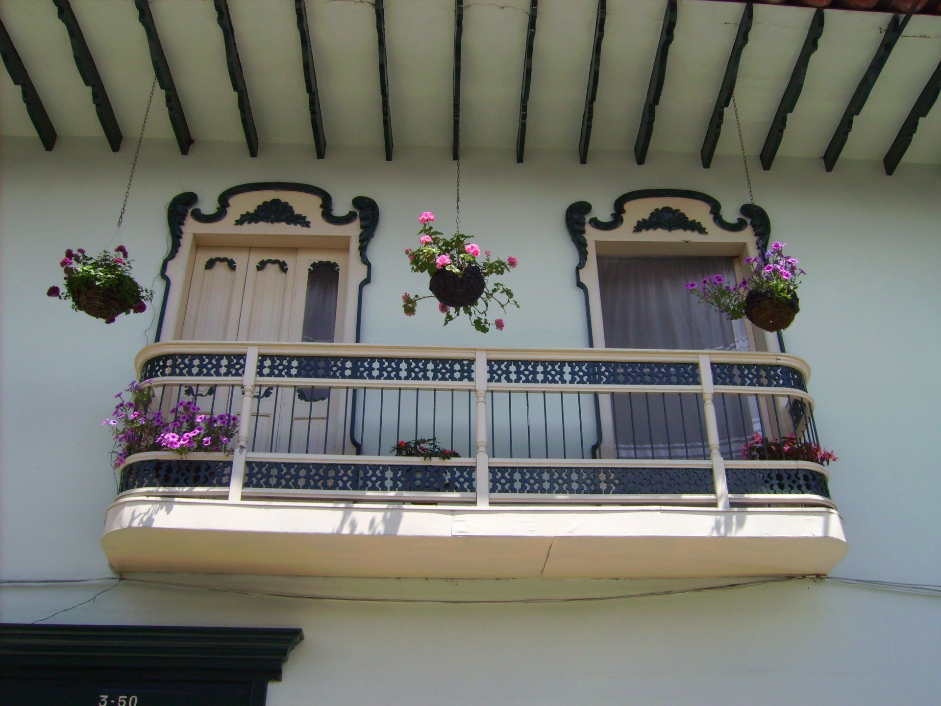 A balcony with hanging baskets of flowers on it