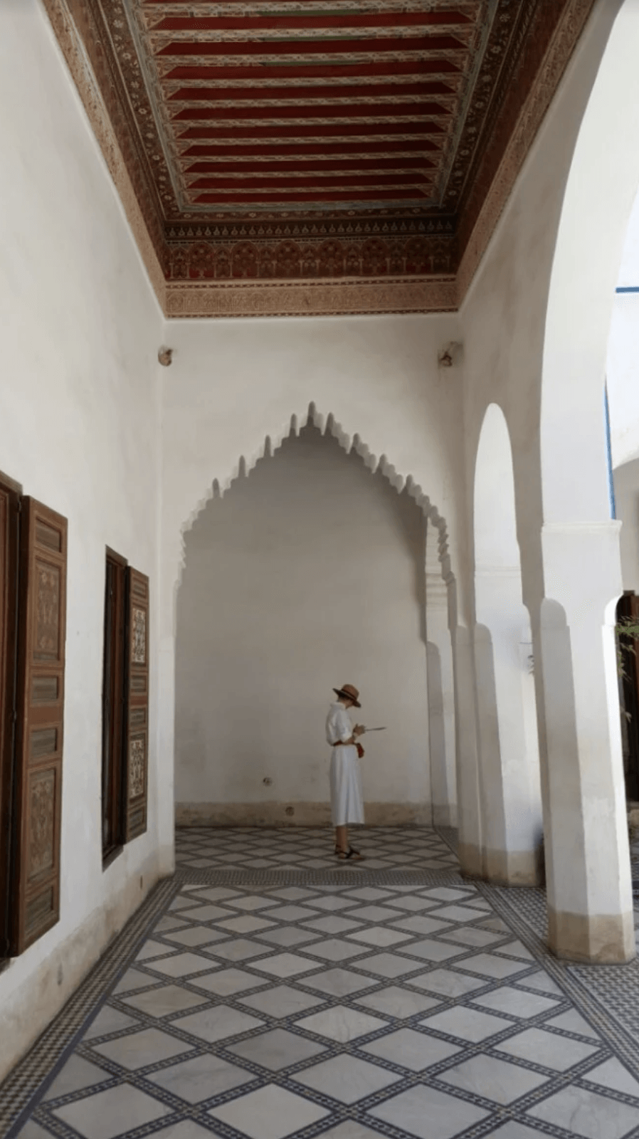 A woman in a white dress is standing in a hallway in a building.