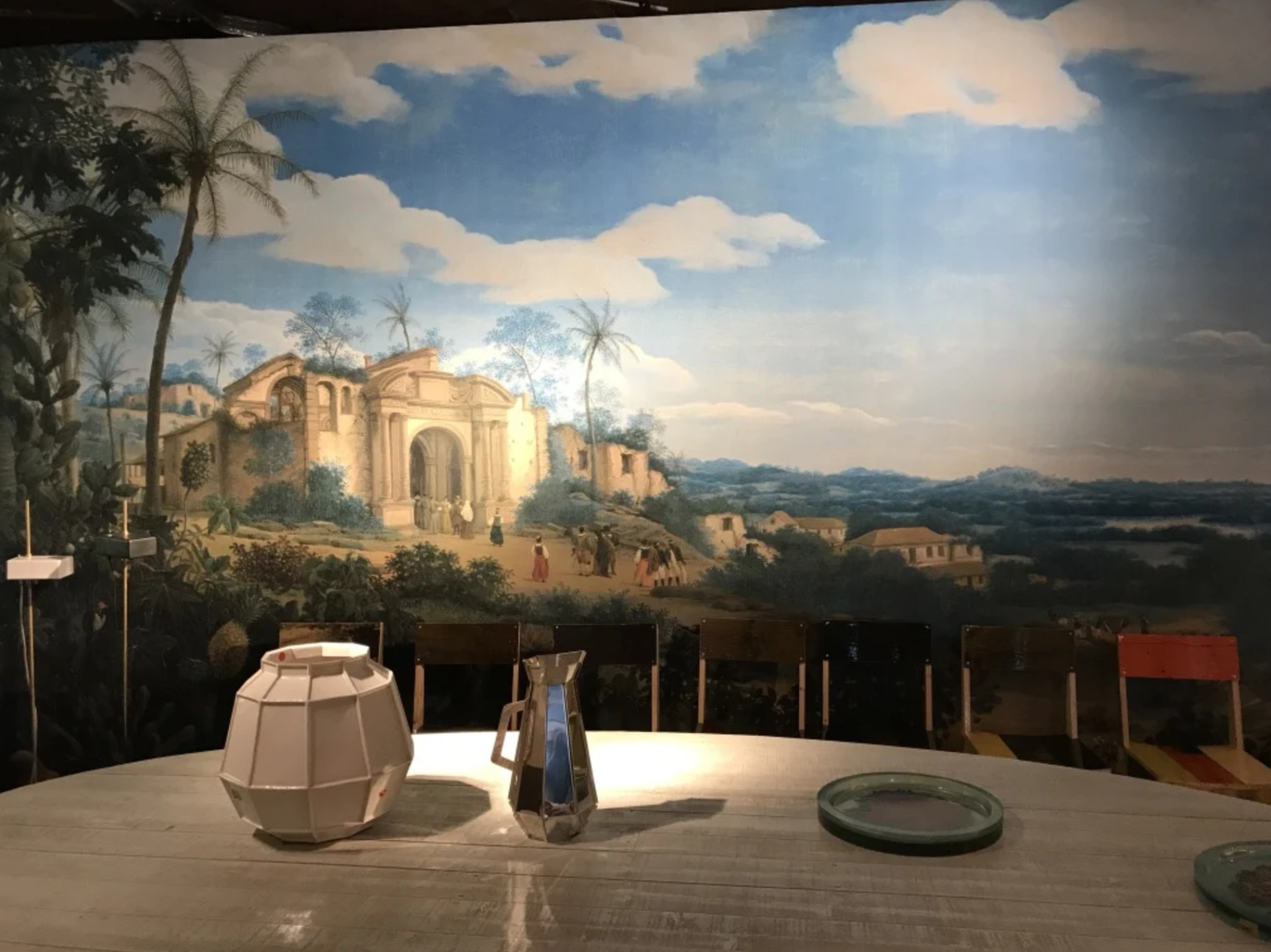 A table with a painting on the wall behind it