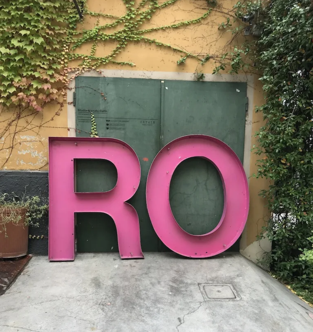 A large pink letter r is in front of a green door