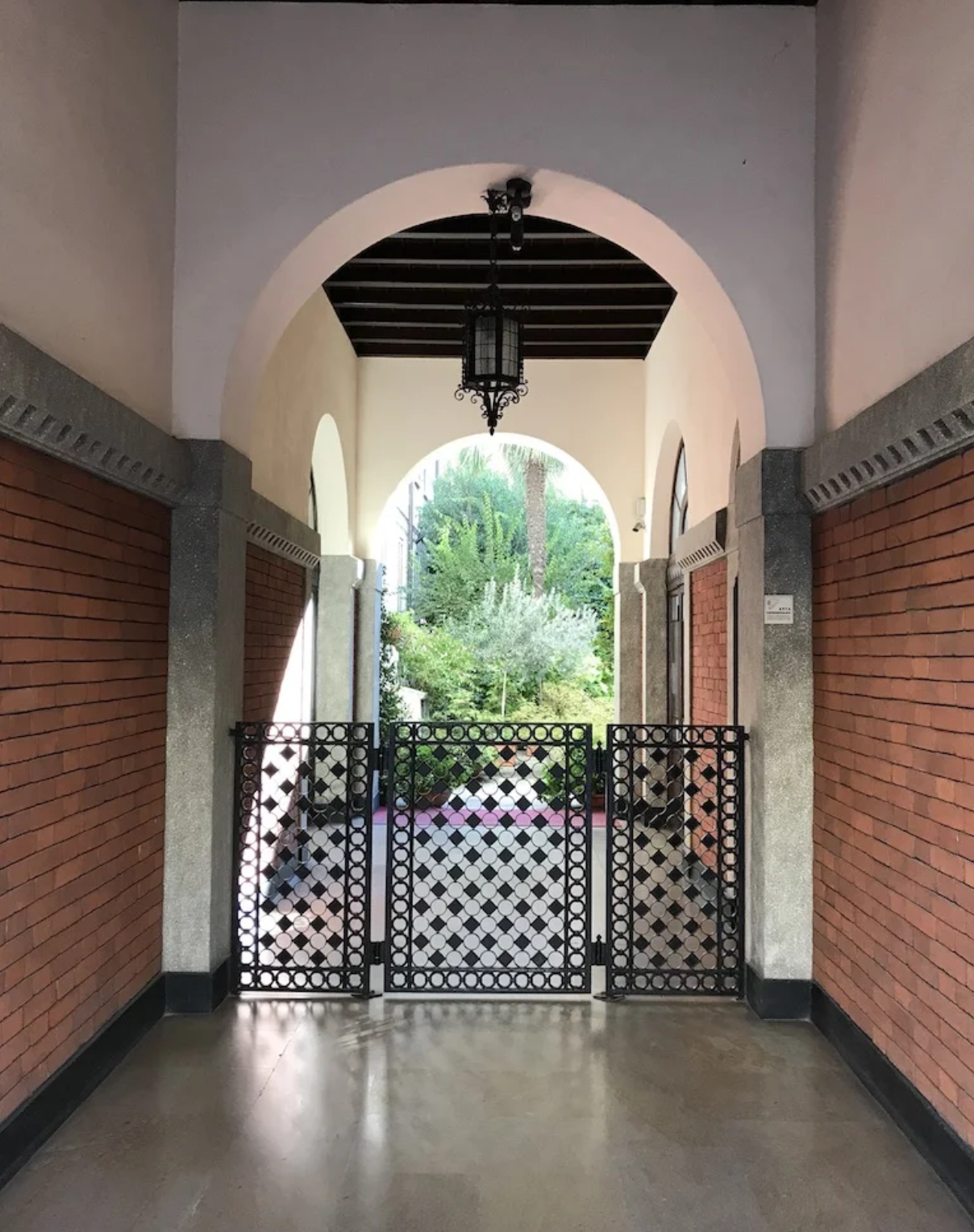 A long hallway with a brick wall and a gate