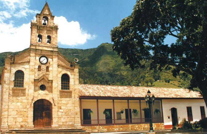 A church with a clock tower and mountains in the background