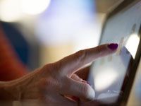 Finger tapping a tablet screen with a bright reflection on the display