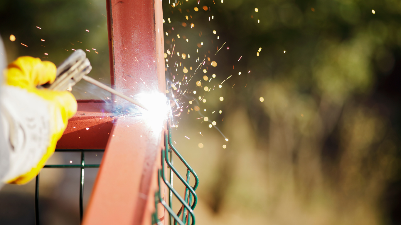 A work truck with open compartments, filled with tools, with a person welding metal outdoors.