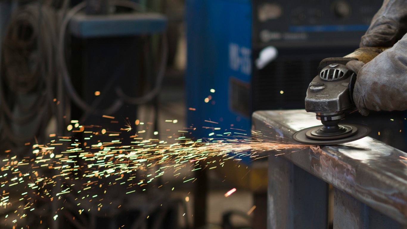 Black railing on a balcony overlooking lush green foliage and pink flowers, with a sunny backdrop.