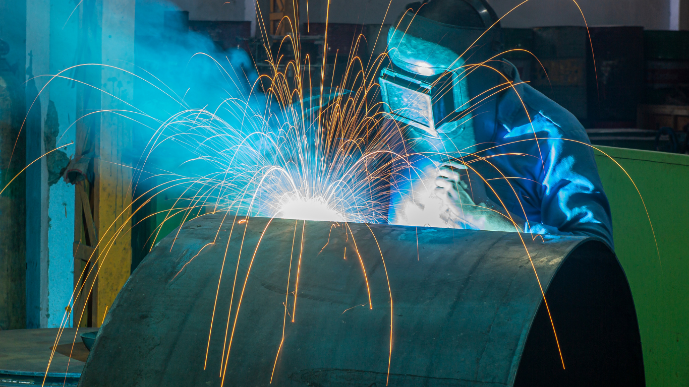 Metal security gate, partially open, with geometric design. Palm trees and blue sky in background.