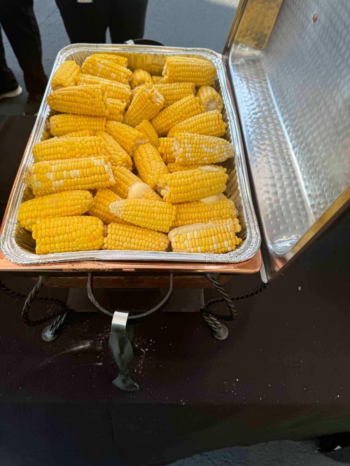 A tray of corn on the cob is sitting on a table.