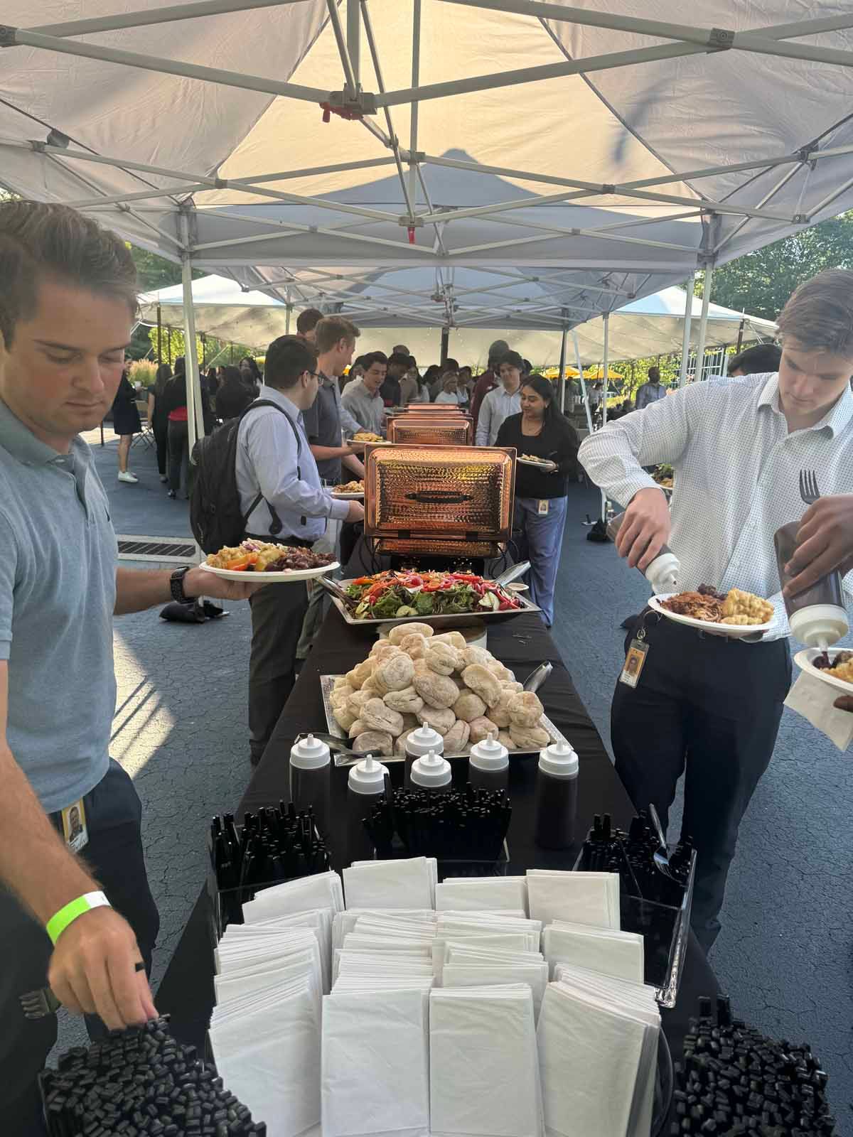 A group of people are standing around a table eating food.