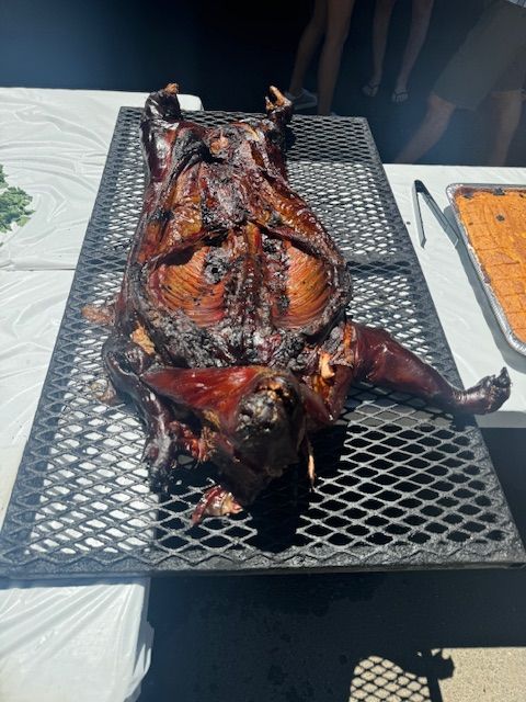 A roasted pig is laying on a grill on a table.