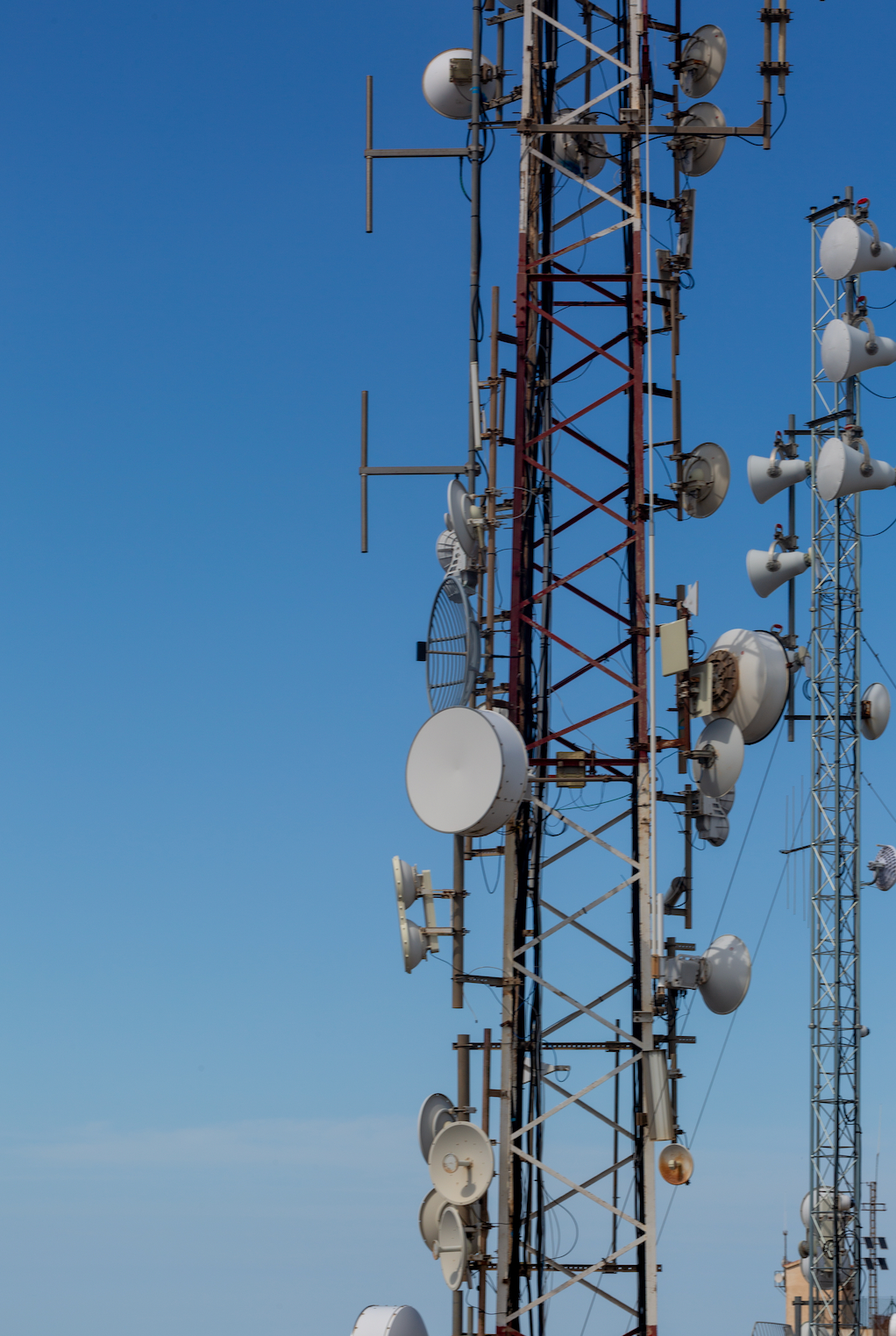 Communication towers against a clear, blue sky, displaying various antennas and dishes.