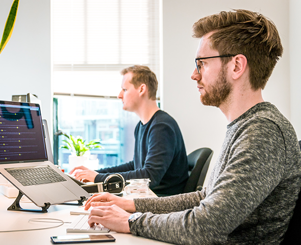 Two men from a Marketing Agency in Council Bluffs are sitting at a desk using laptops.