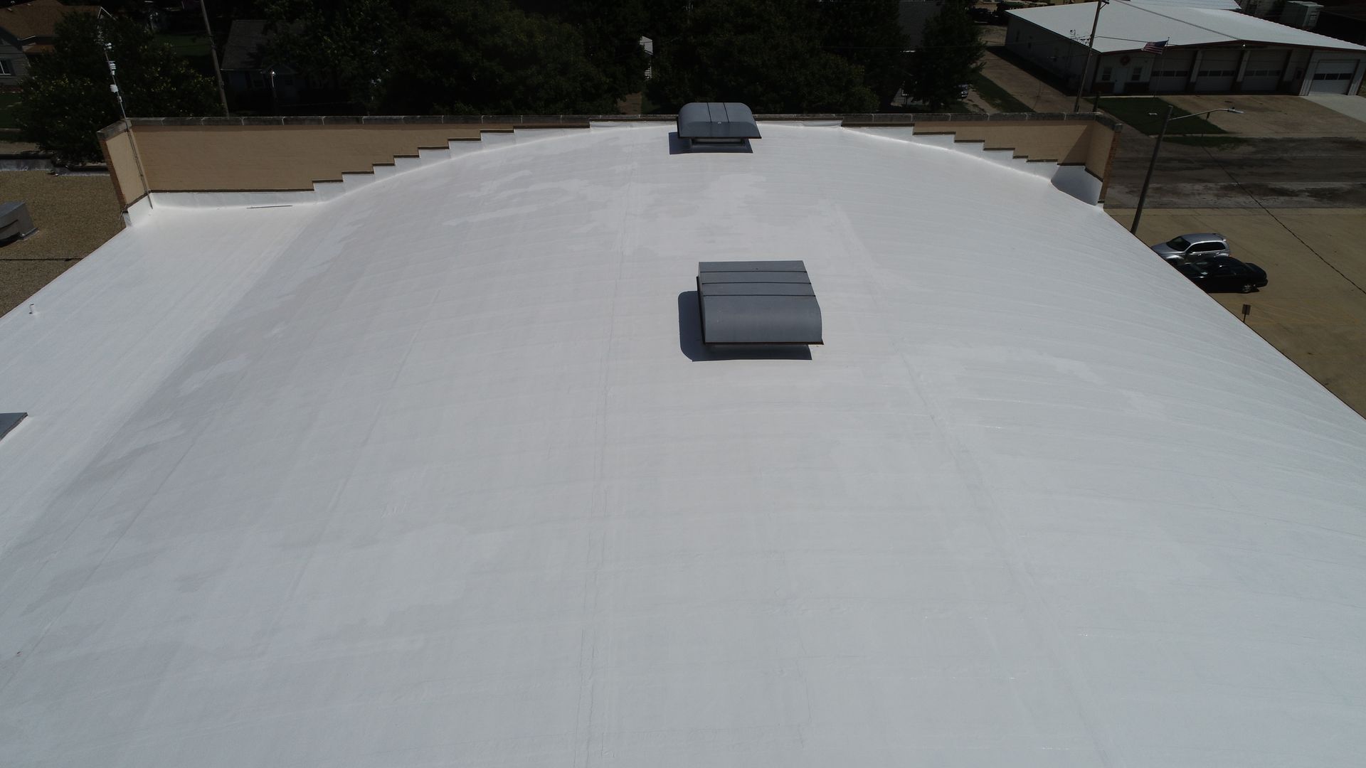 White roof coating system enhancing durability on a unique barrel roof structure.