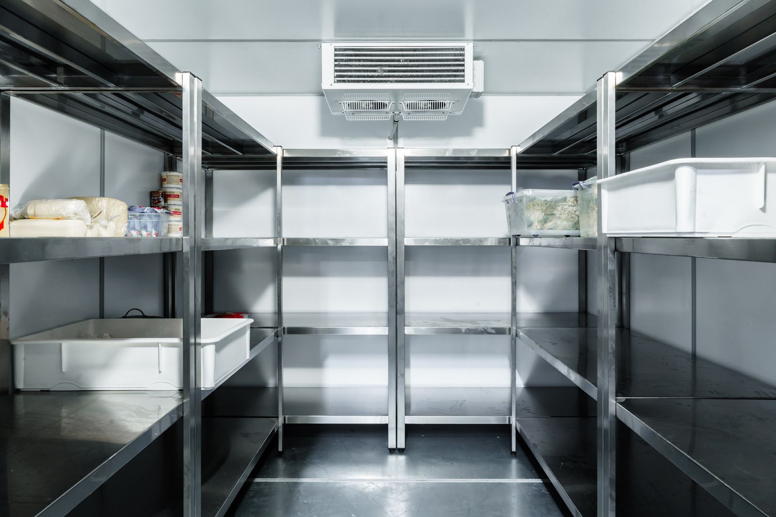 An empty refrigerator with stainless steel shelves and boxes.