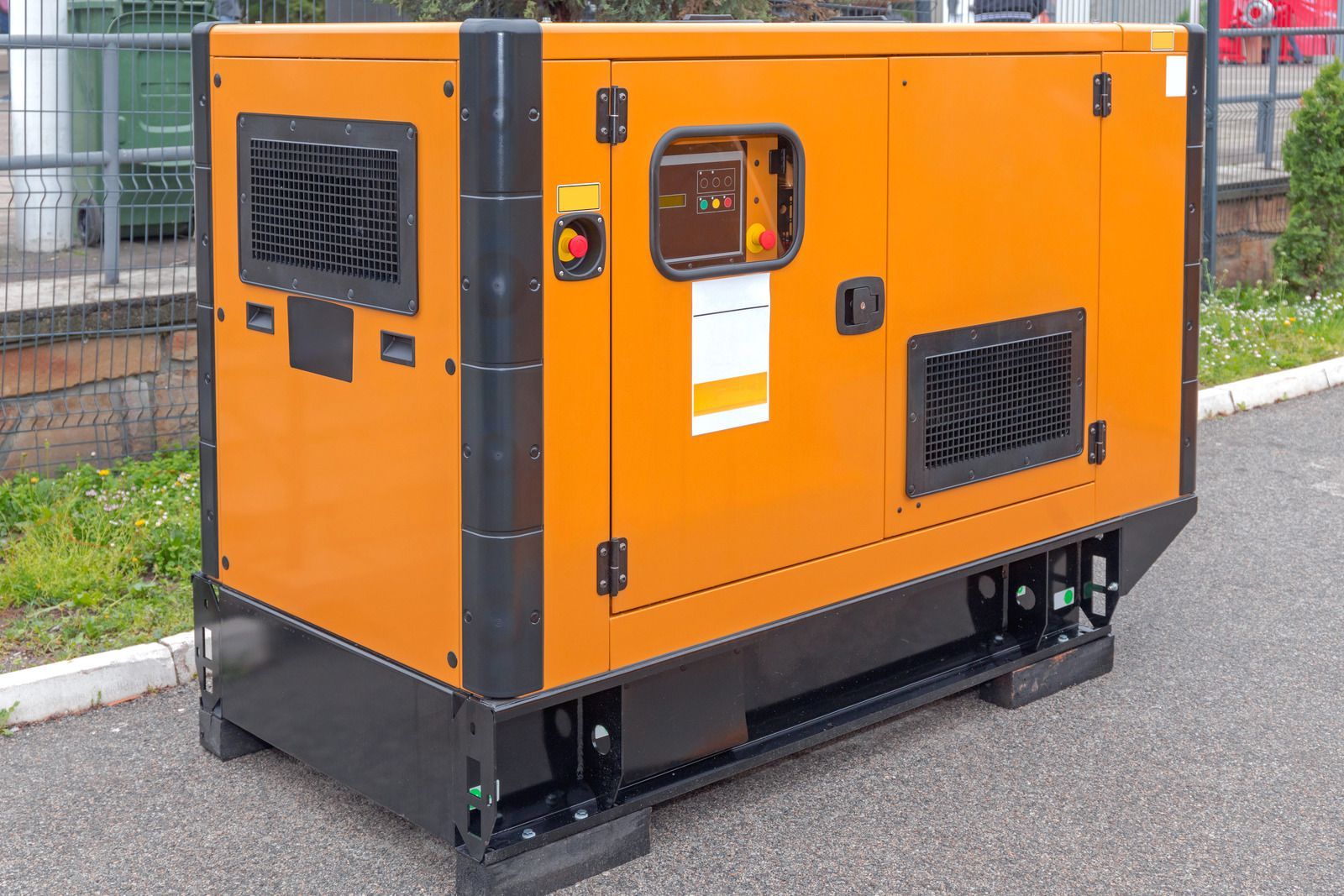 An orange and black generator is parked on the side of the road.