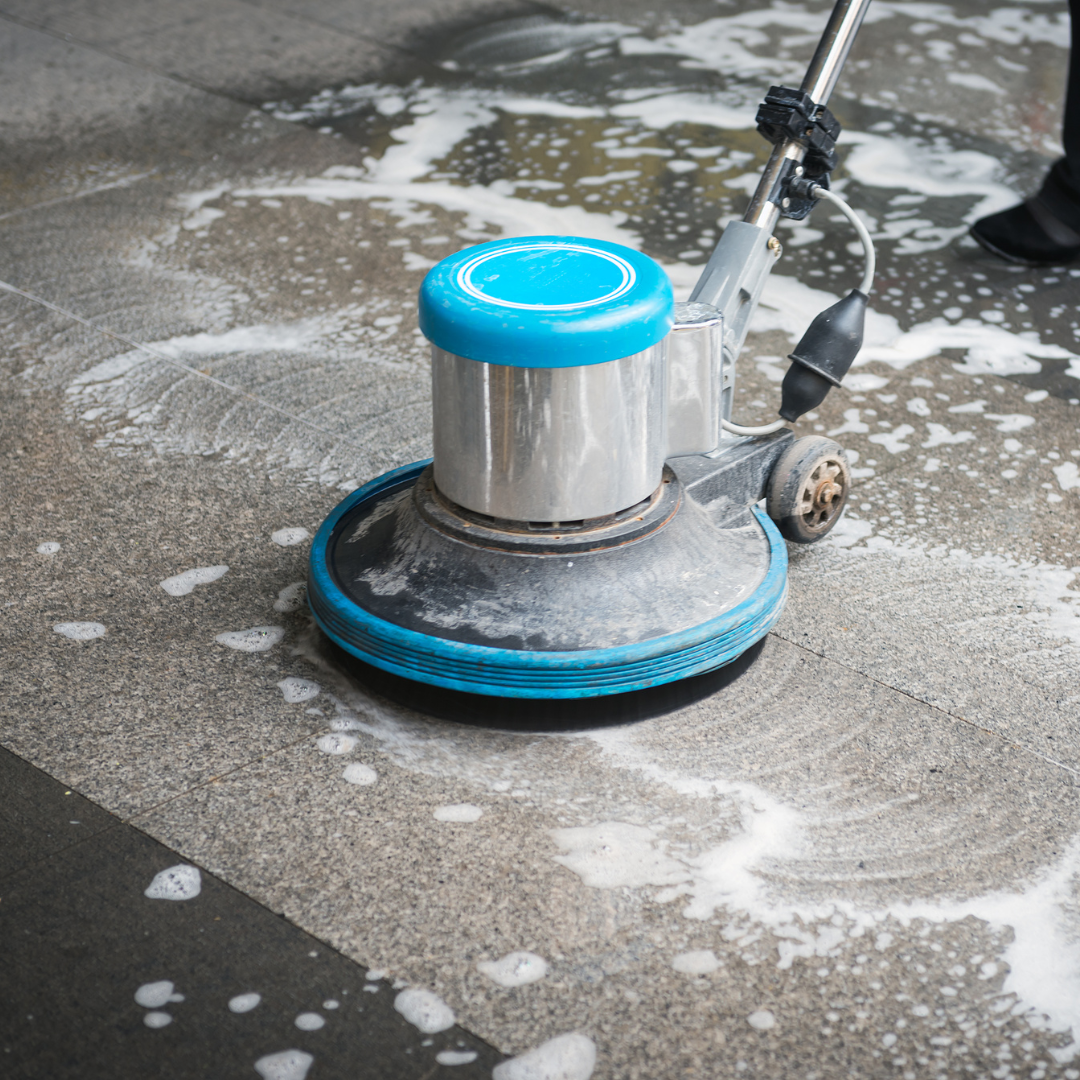 A person is cleaning a tiled floor with a machine.