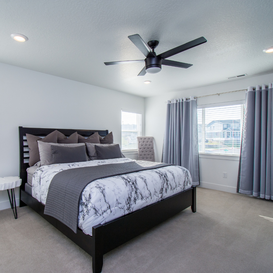 A bedroom with a large bed and a ceiling fan