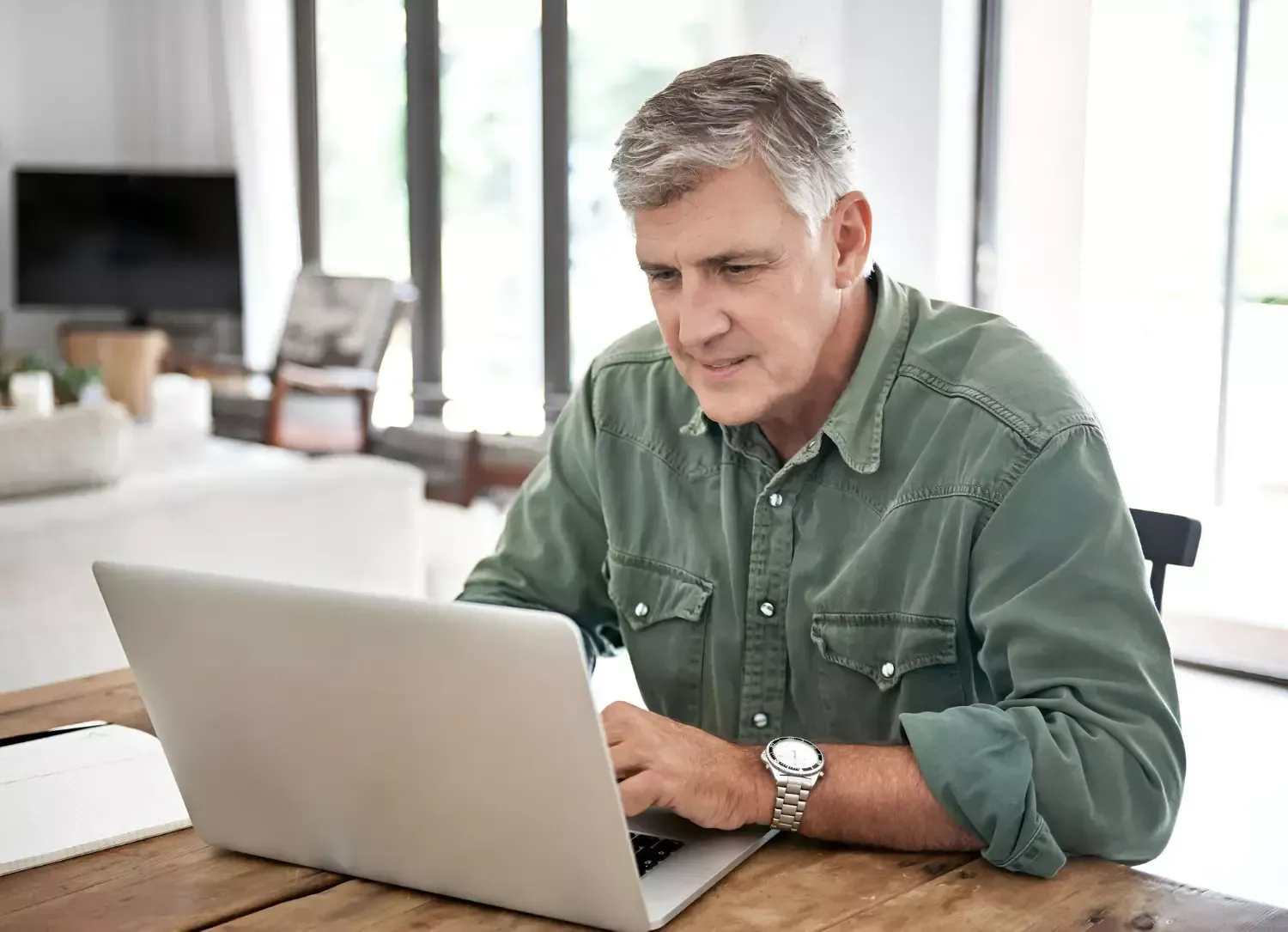 Um homem está sentado à mesa usando um laptop.