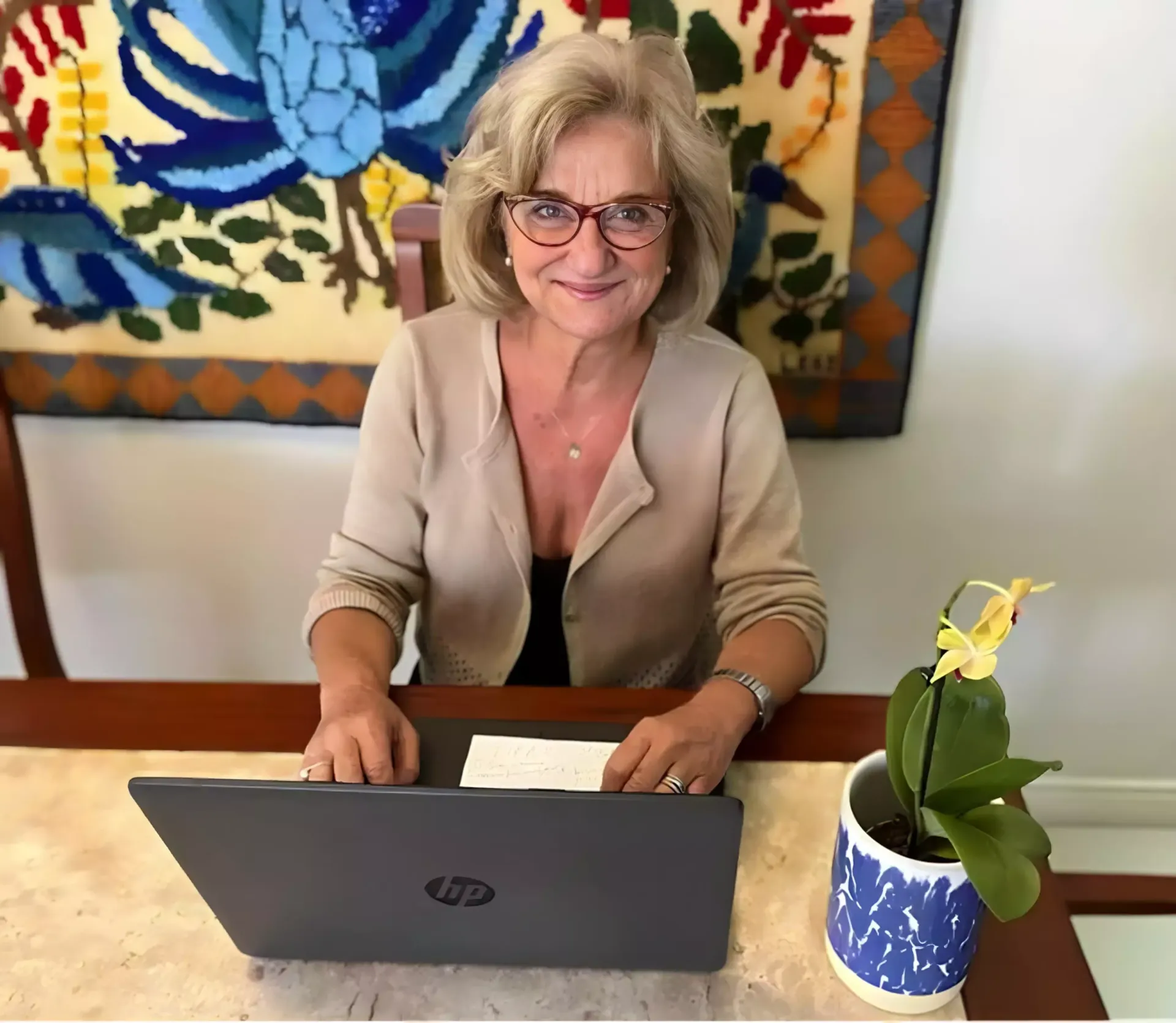 Uma mulher está sentada à mesa usando um laptop hp