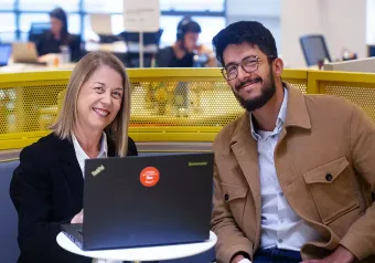 Um homem e uma mulher estão sentados à mesa com laptops.