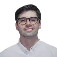 Um jovem usando óculos e camisa branca está sorrindo.