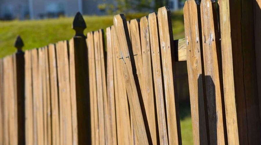 Damaged wooden fence with loose and leaning pickets